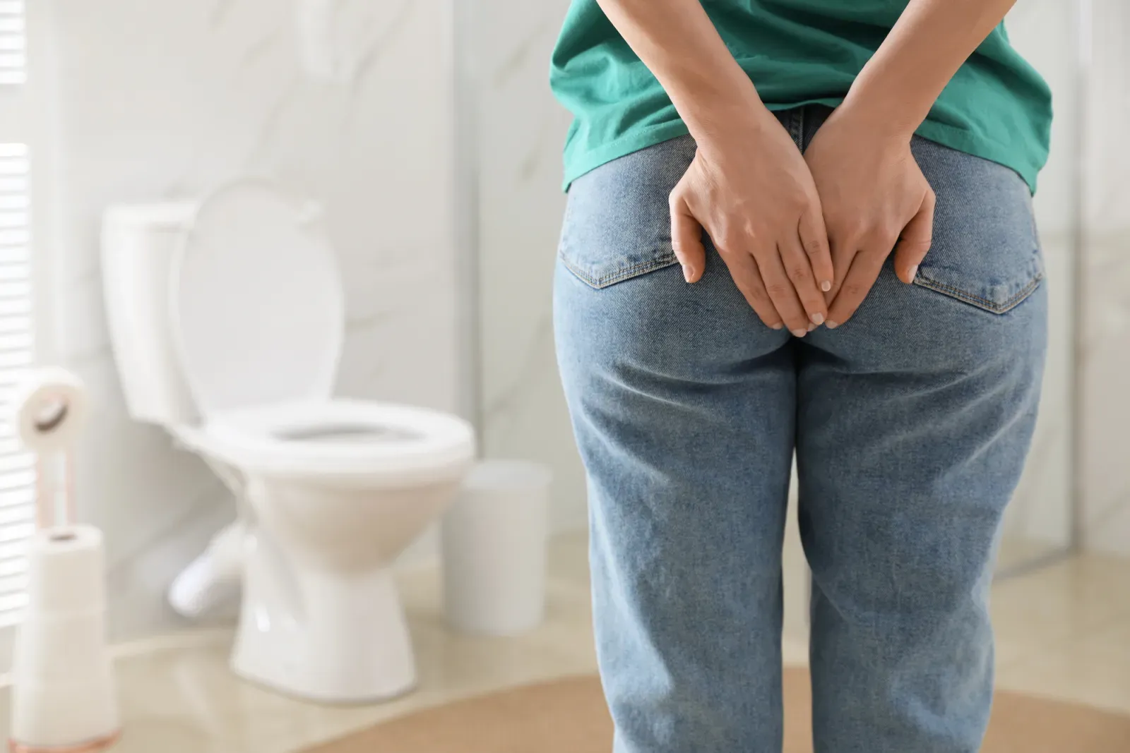 A person standing in a bathroom beside a toilet, hands held behind them