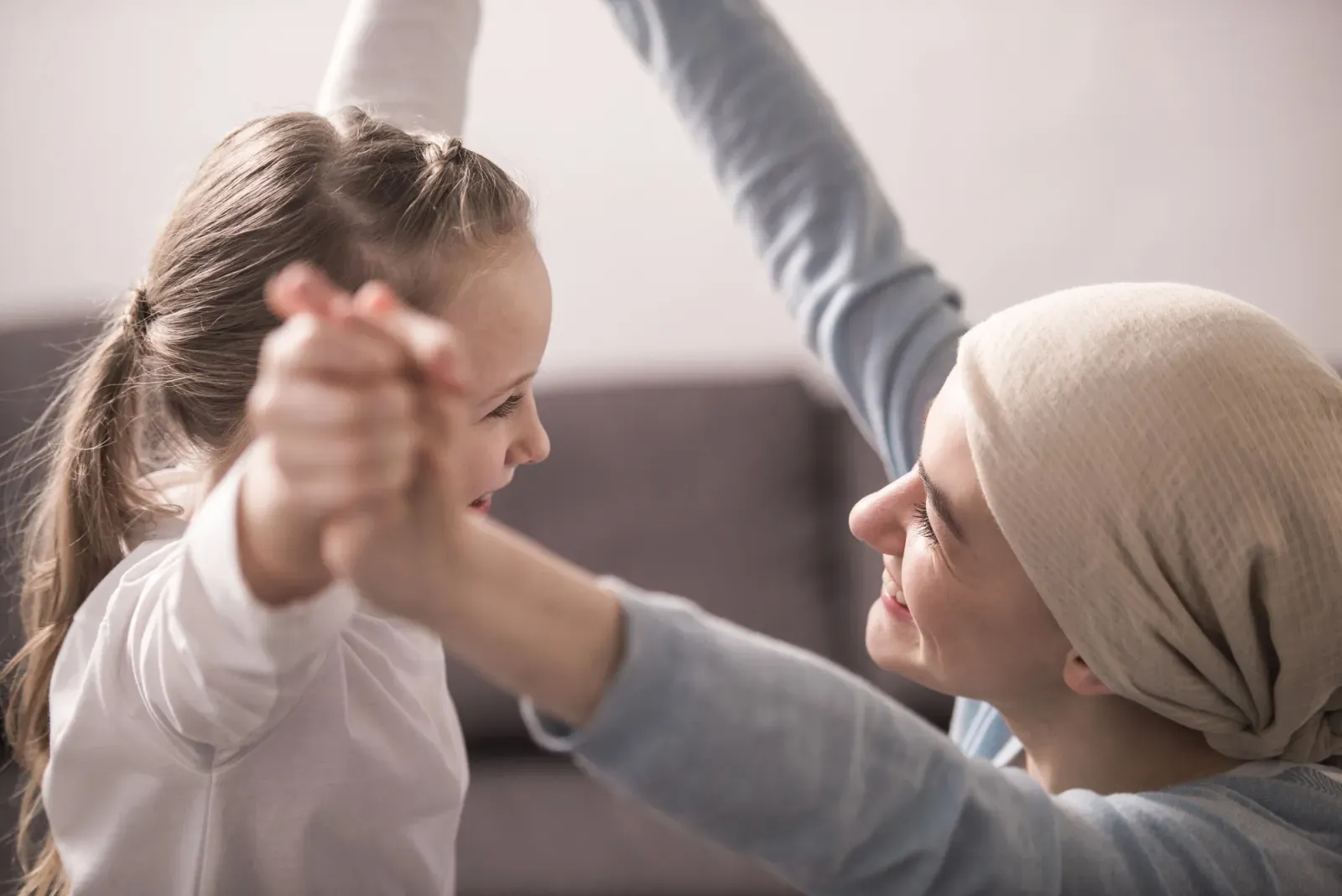 A girl dancing with a woman wearing a headscarf, both smiling